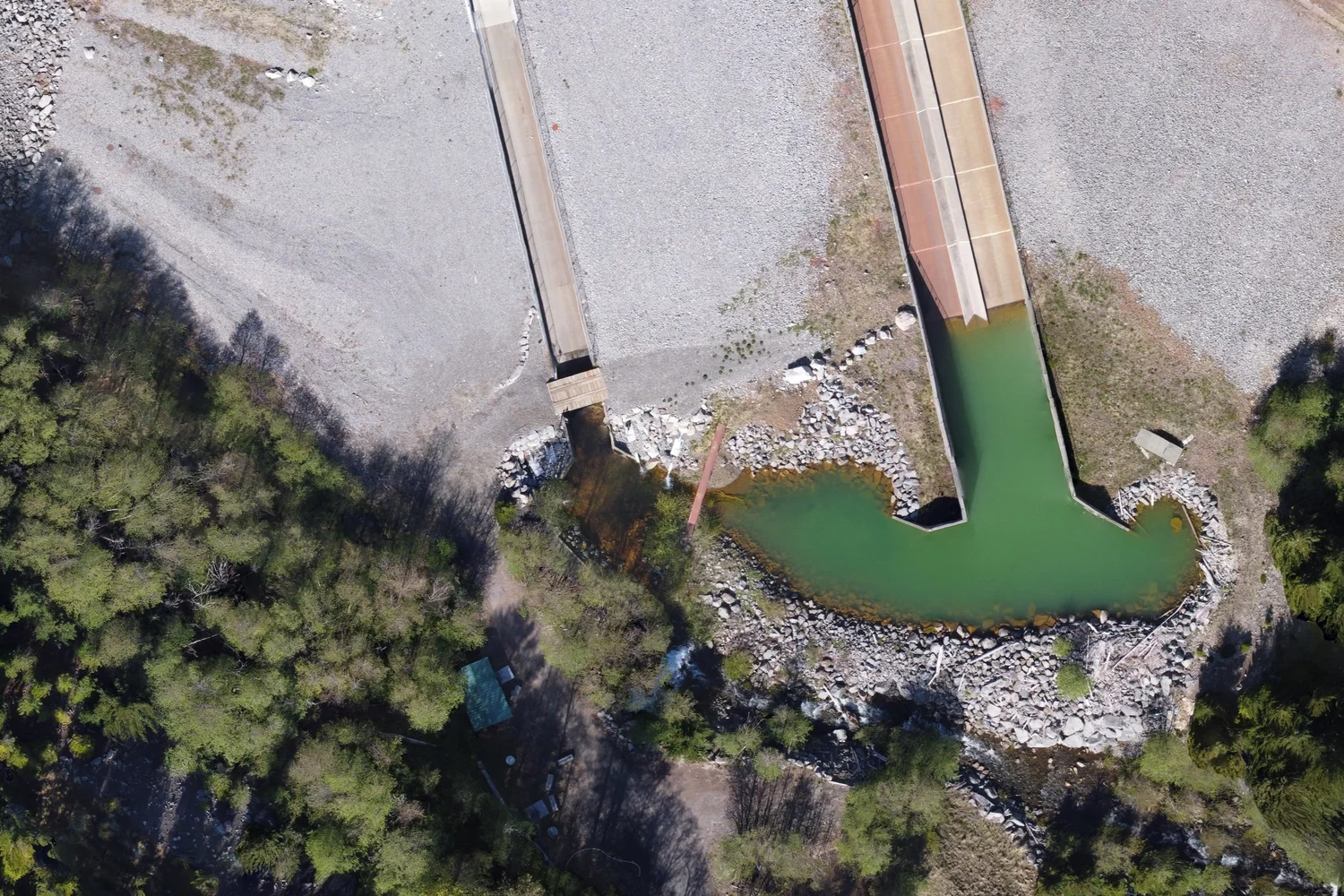 Overhead drone image of a dam structure, spillways, and water channels